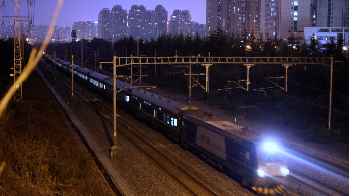 夜间绿皮火车快速行驶 火车穿过城市