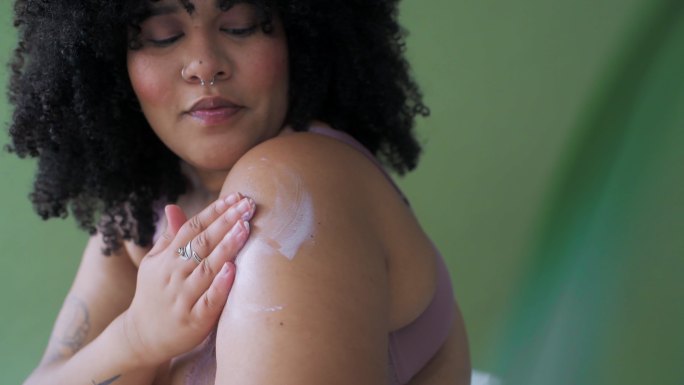 一位女性独自在皮肤上涂抹美容产品