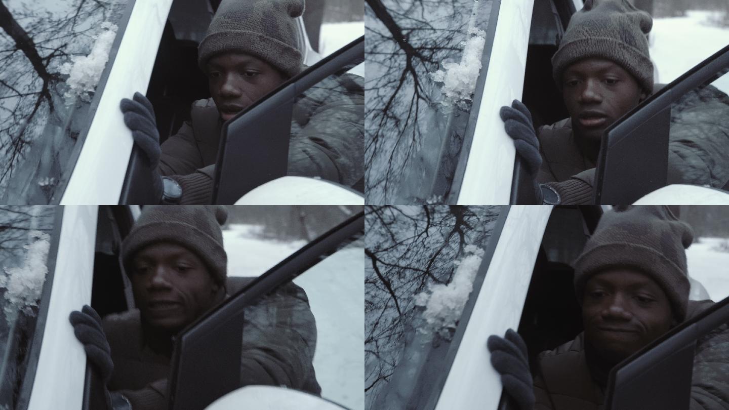男人在积雪的公路上推着汽车试图启动引擎。