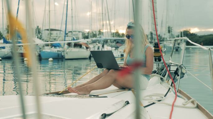 美丽的女士在帆船上使用笔记本电脑
