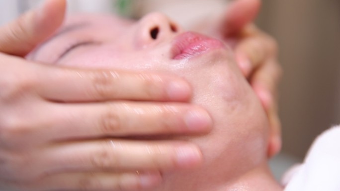 水疗养生俱乐部的迷人女性接受面部按摩