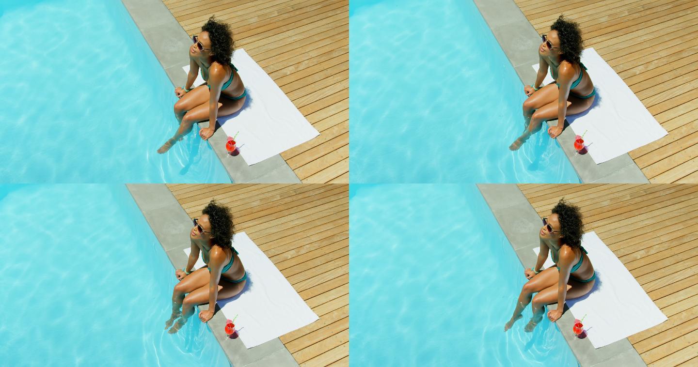 在游泳池中浸泡双脚的年轻女子