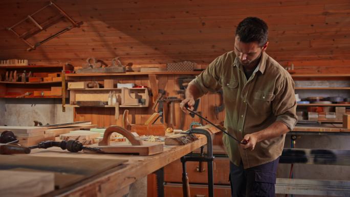 男木匠在他的店里用拉刀塑造一块木头