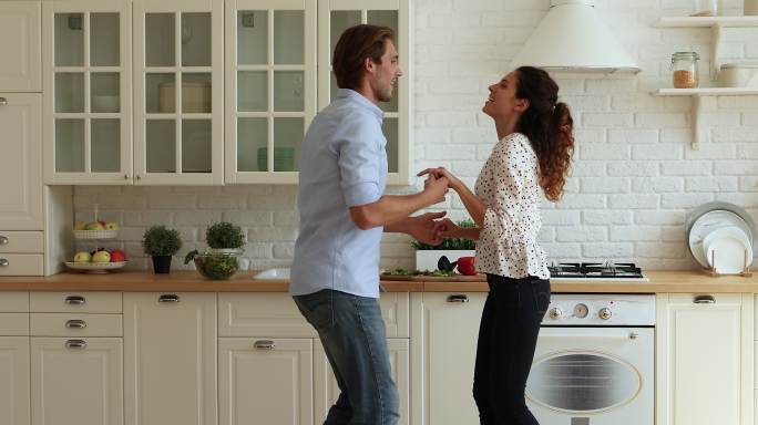 精力充沛的情侣手牵手在厨房跳舞