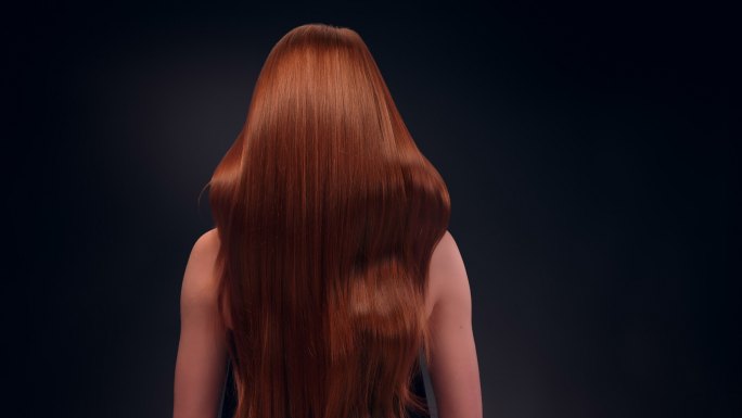 美丽的红发女人甩着她的长发