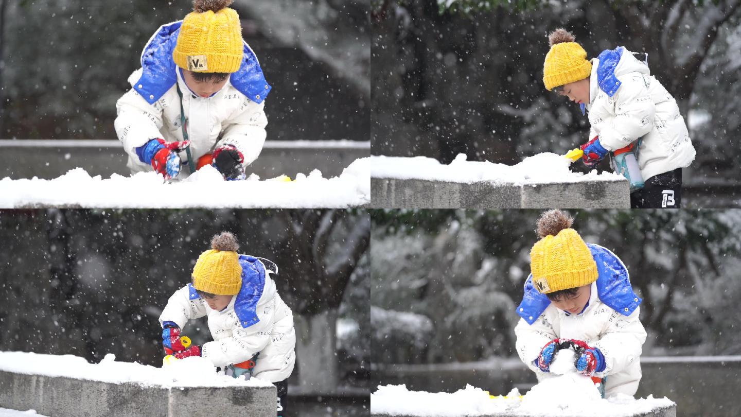 下雪天认真堆雪人的小男孩