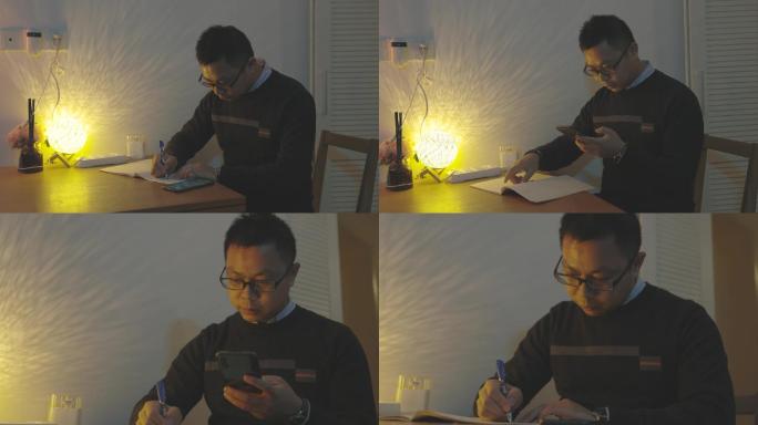 一名男子深夜在桌前看着手机写资料
