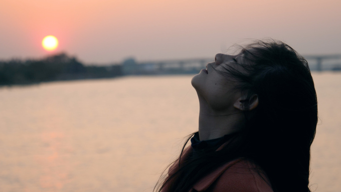 伤感女孩在夕阳下的河边吹风4k视频素材