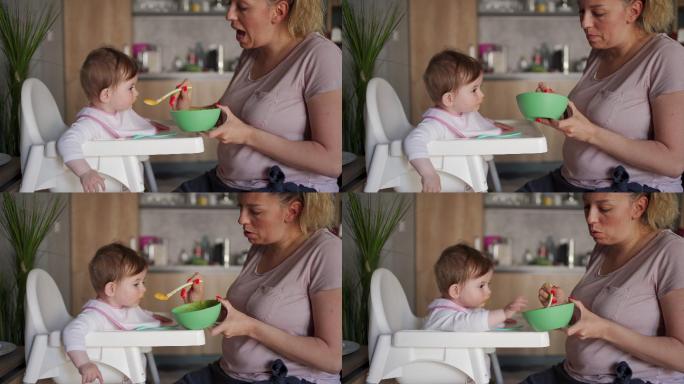 母亲用勺子给女婴喂有机胡萝卜泥