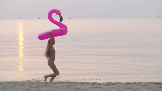 年轻女子拿着游泳圈在沙滩奔跑
