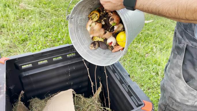 男子将有机垃圾桶和食物残渣倒入堆肥机