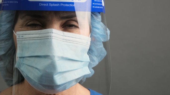 精疲力竭的医护人员戴着口罩和面罩看着镜头