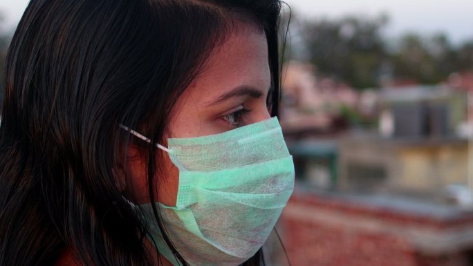 妇女用防污口罩遮住脸，以防感染病毒