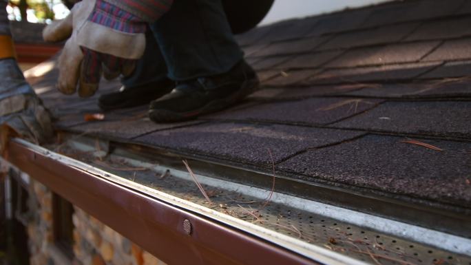 一个女人清洁屋顶排水沟的视频。
