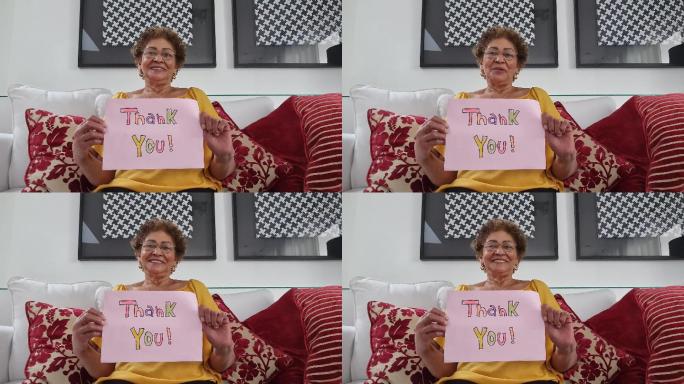 女士在视频通话中展示写有“谢谢”的纸张