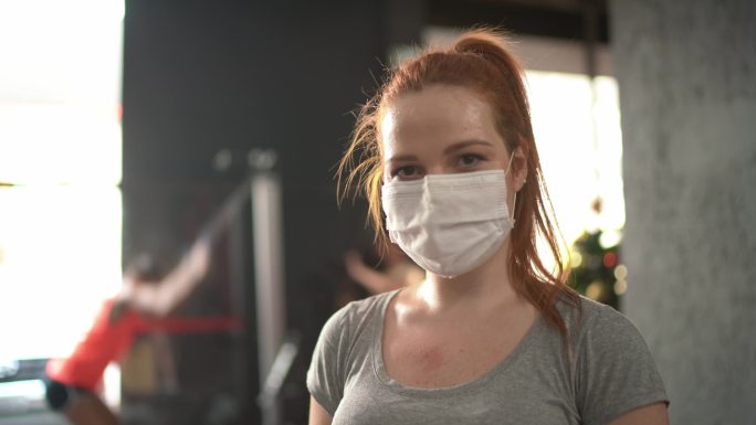 一位年轻女子在健身房使用口罩的肖像