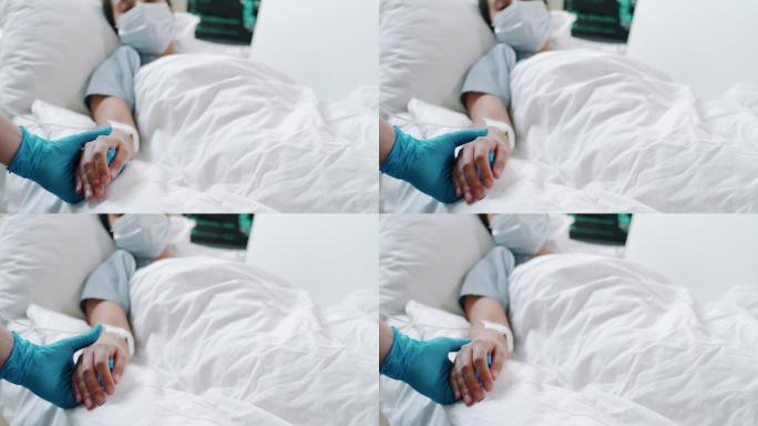 戴防护手套的护士抚摸女性冠状病毒患者的手