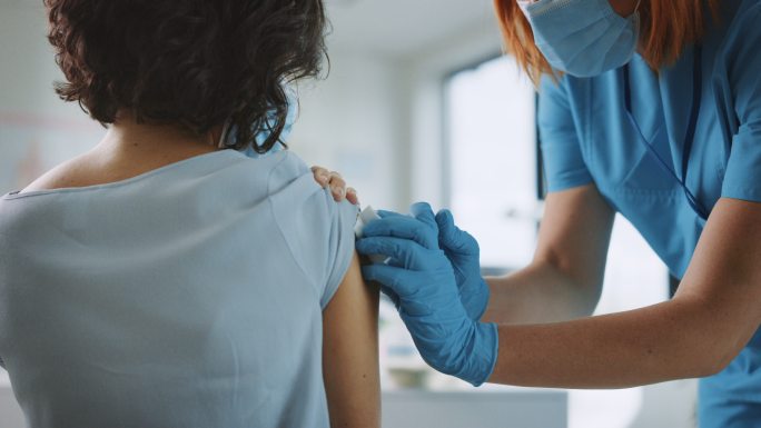 医护人员正在为一名女性患者注射疫苗。
