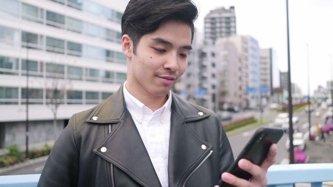 年轻男性在街道上使用智能手机
