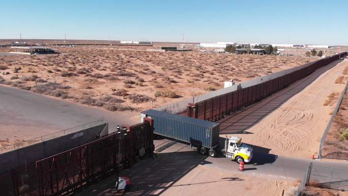 卡车经过美墨边境墙，前往美国海关进口货物