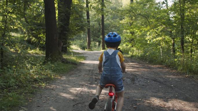 快乐的小男孩在夏季公园骑自行车