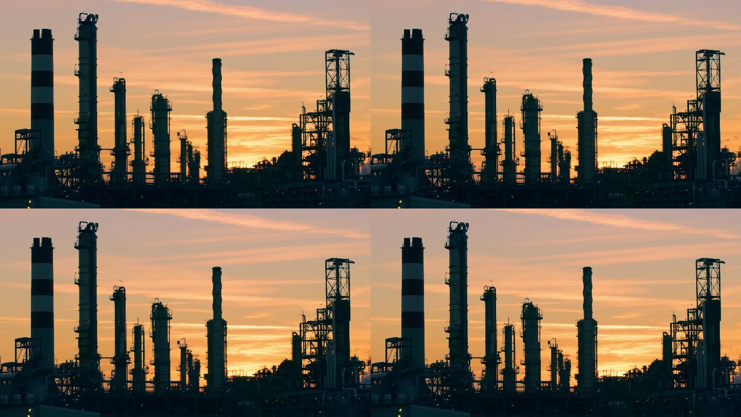 日落的天空衬托出炼油厂烟囱的轮廓