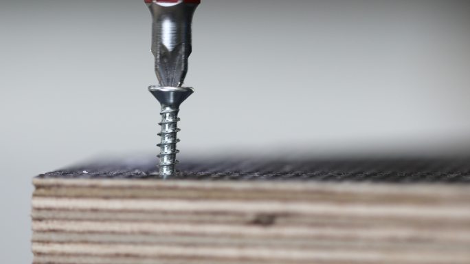 电钻把螺丝钉在木板上。