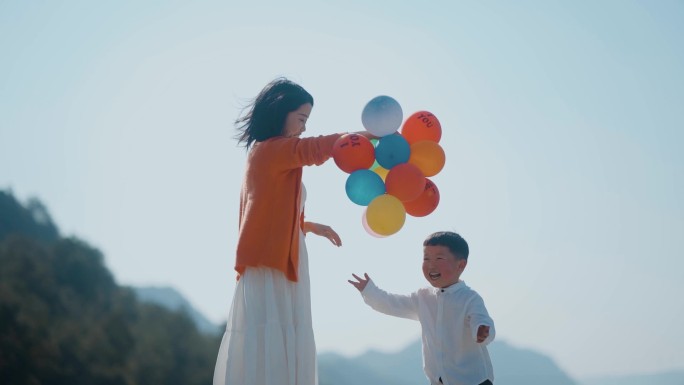 温馨母亲陪小孩玩气球小孩高兴蹦蹦跳跳母爱