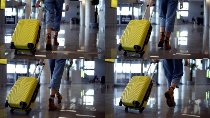 时尚的女士在空旷的机场拉着行李箱