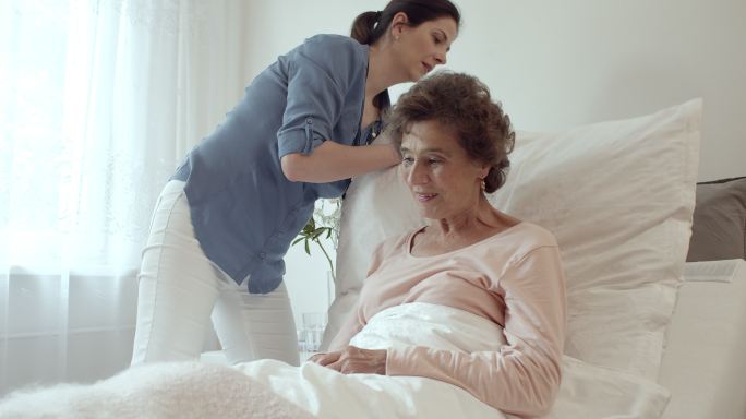 家庭护士为老年女性病人铺床。