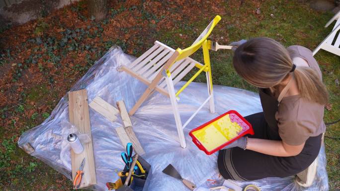 年轻女性在后院粉刷椅子
