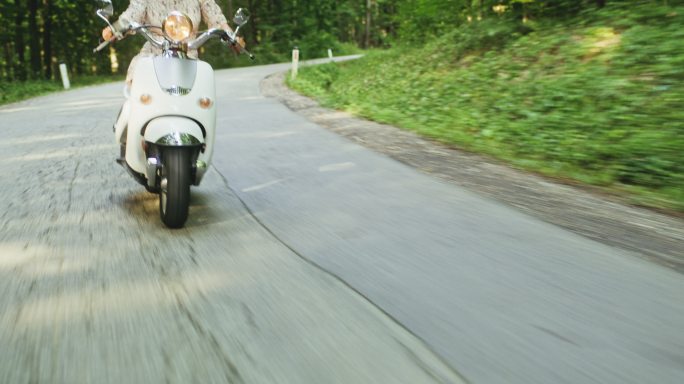 一个妇女骑着摩托车穿越森林的广角镜头