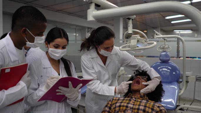 患者躺在牙医椅上张嘴，教师向学生解释