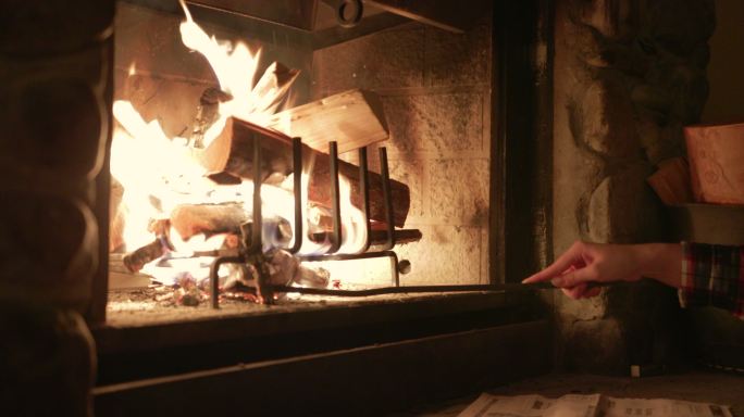 妇女在冬季小屋的壁炉里燃烧木头