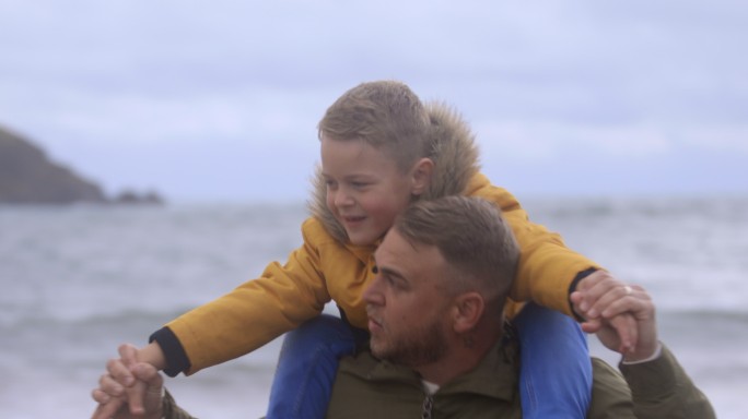 海滩上坐在爸爸的肩膀上的儿子