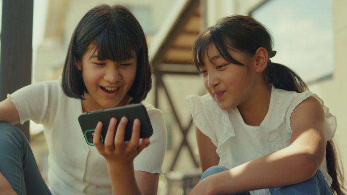 两个年轻女孩一起看智能手机