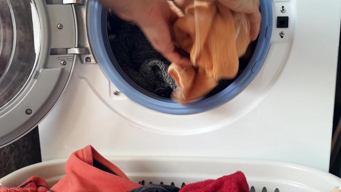男人把脏衣服扔进洗衣机里