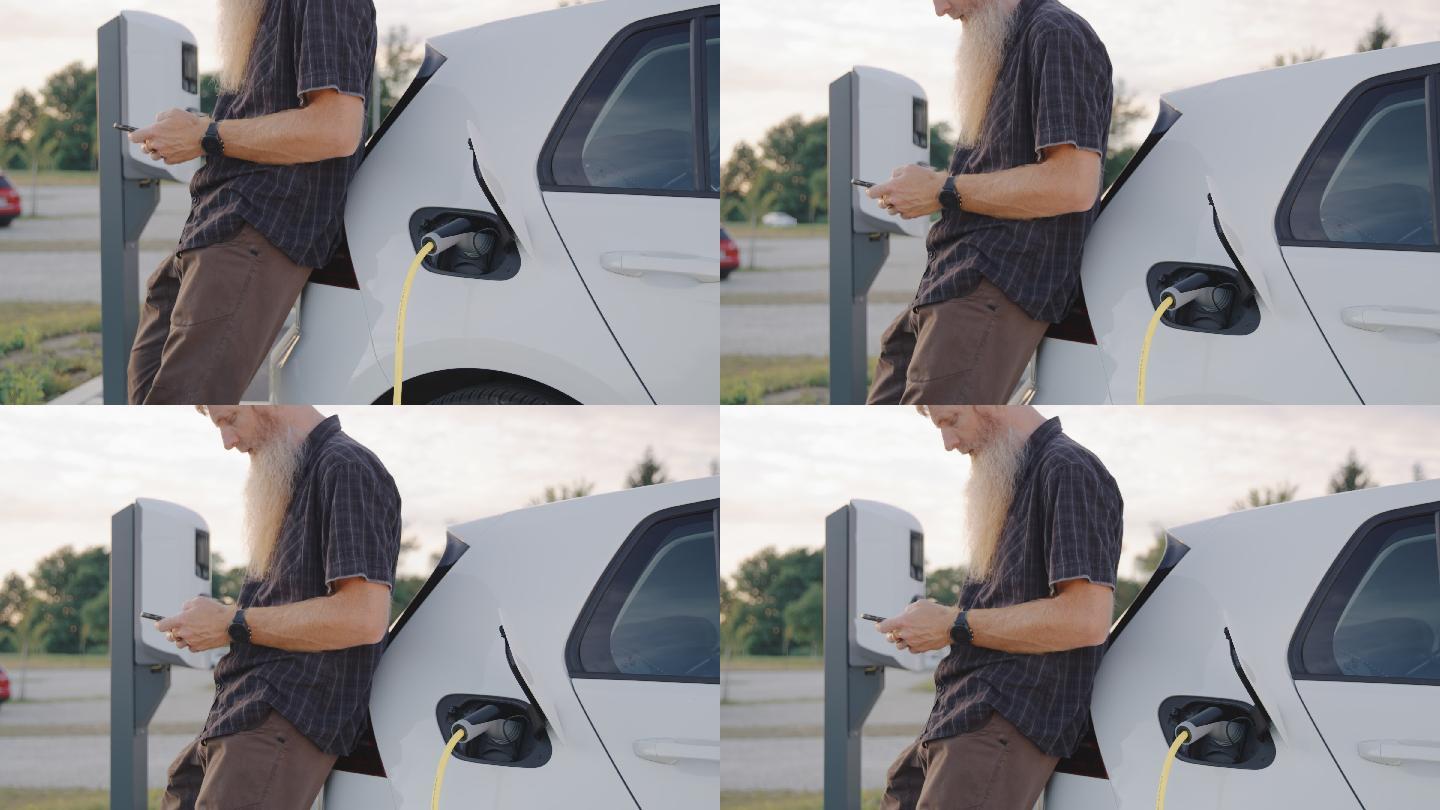 男子在停车场的充电站等待充电时用智能手机