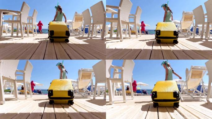 在海滩上拉着黄色手提箱的顽皮女孩
