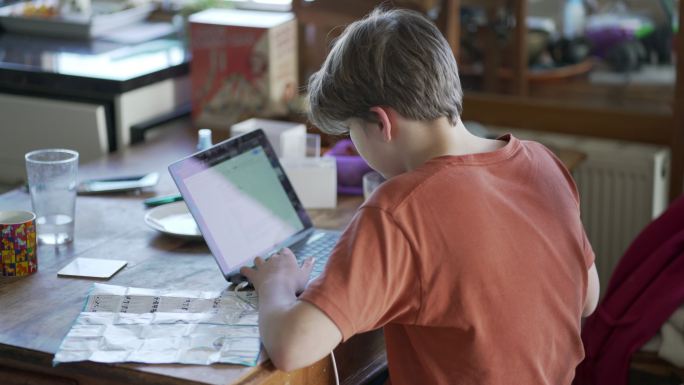 一个十几岁的男孩在家里做功课