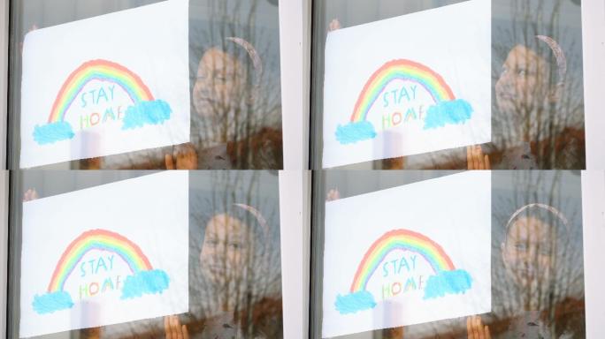 一个女孩把彩虹的图画放在窗户上