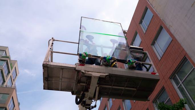 工人将双层玻璃运送到升降平台上的安装位置