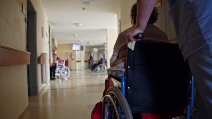 护士推着轮椅上的老妇人