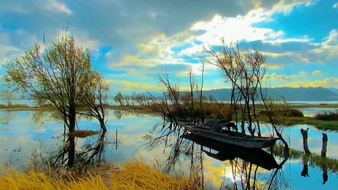 蓝天白云树木掩映平静的湖泊上停泊着一小船