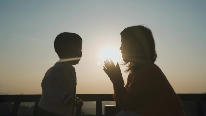 逆光人物剪影妈妈陪伴孩子亲吻额头温馨家庭