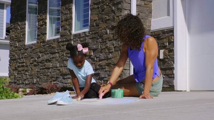 小女孩在人行道上用粉笔画画