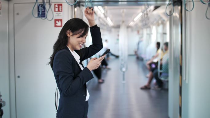 女商人在上下班途中在火车上使用智能手机