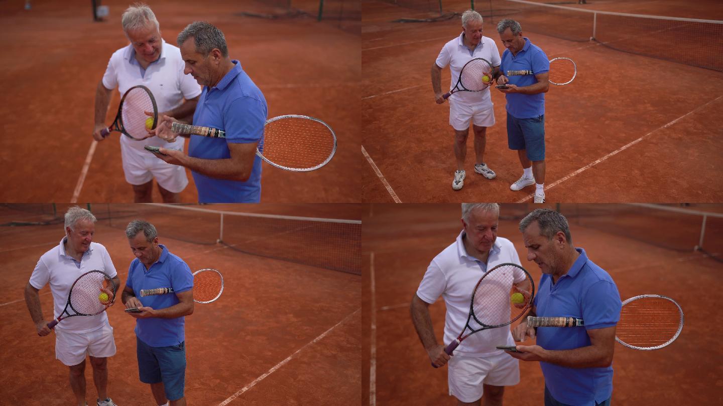 男子在网球场上一起使用智能手机