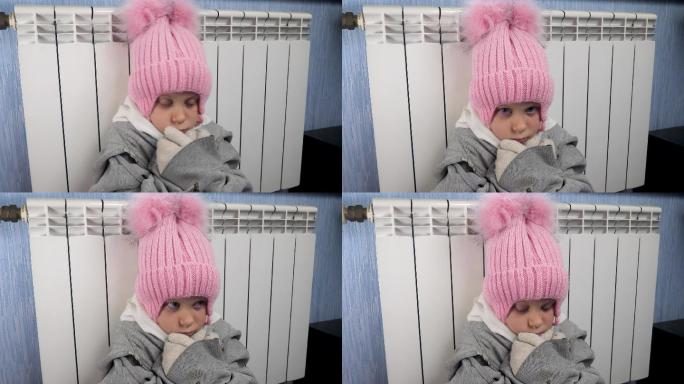 小女孩坐在暖气旁可爱的小女孩寒冷的女孩暖