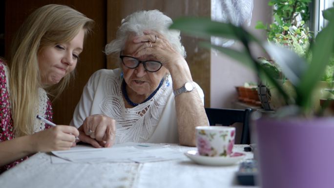 年轻女子帮助年迈的祖母做文书工作